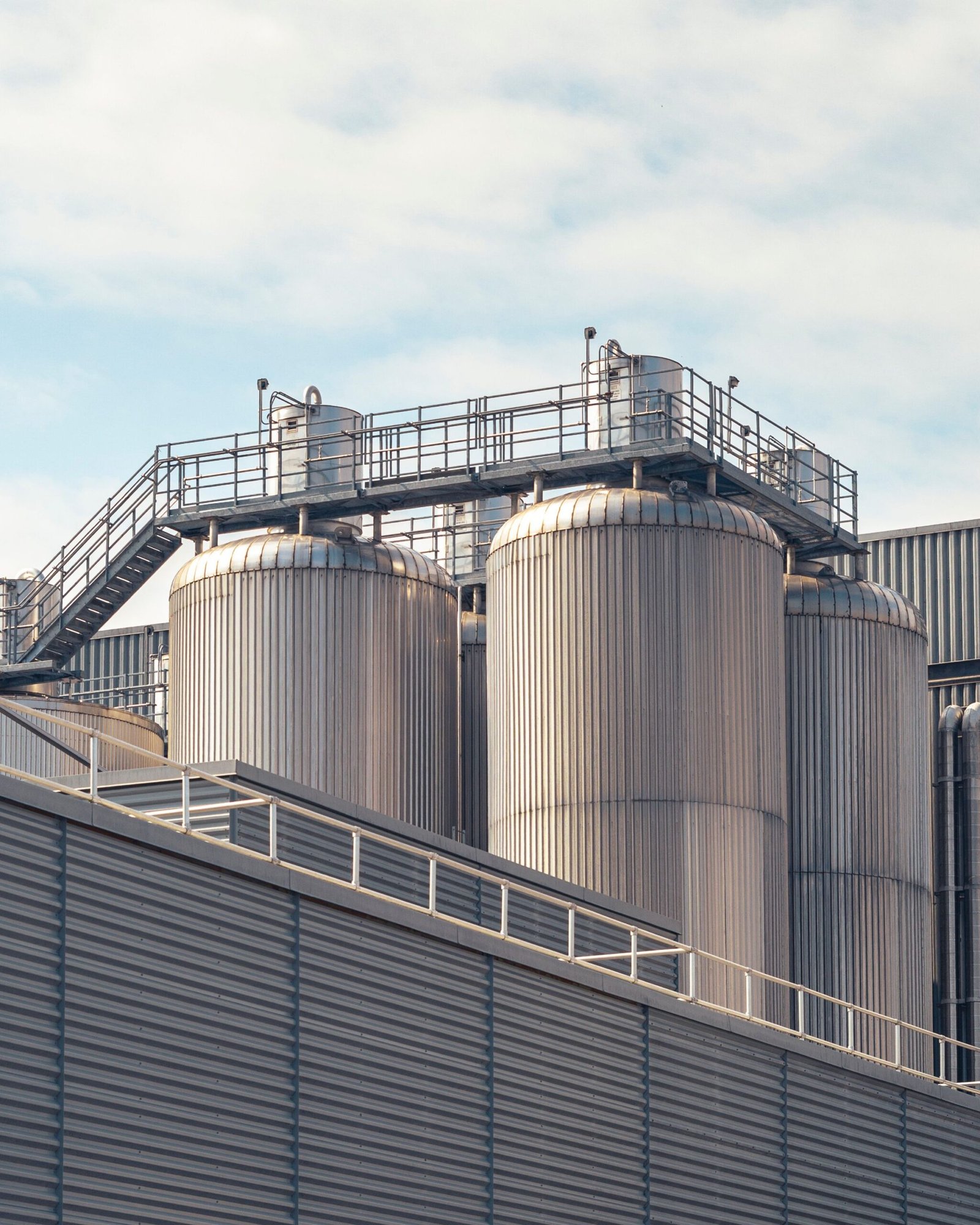 aerospace A view of metal storage tanks outside an industrial facility under a partly cloudy sky.