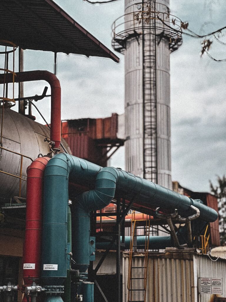 aerospace View of an industrial facility showcasing colorful pipes and structures under a cloudy sky.