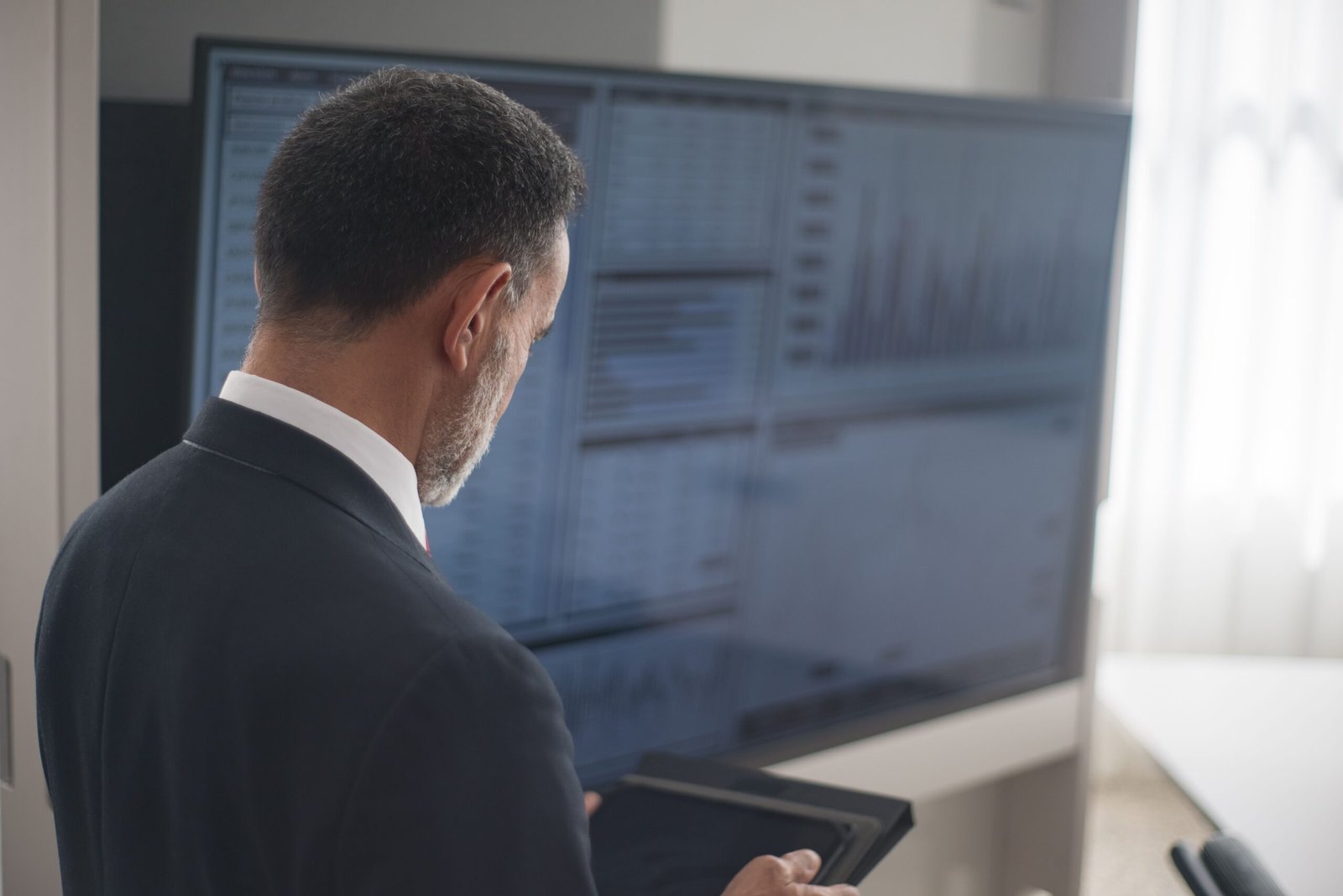 Home Professional analyzing stock markets on a digital tablet in a modern office setting.
