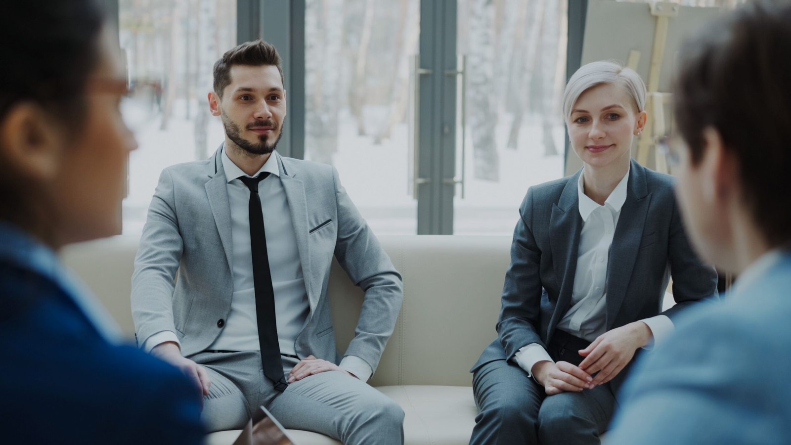 Partner With Us Business meeting with professionals in suits discussing in a modern office.